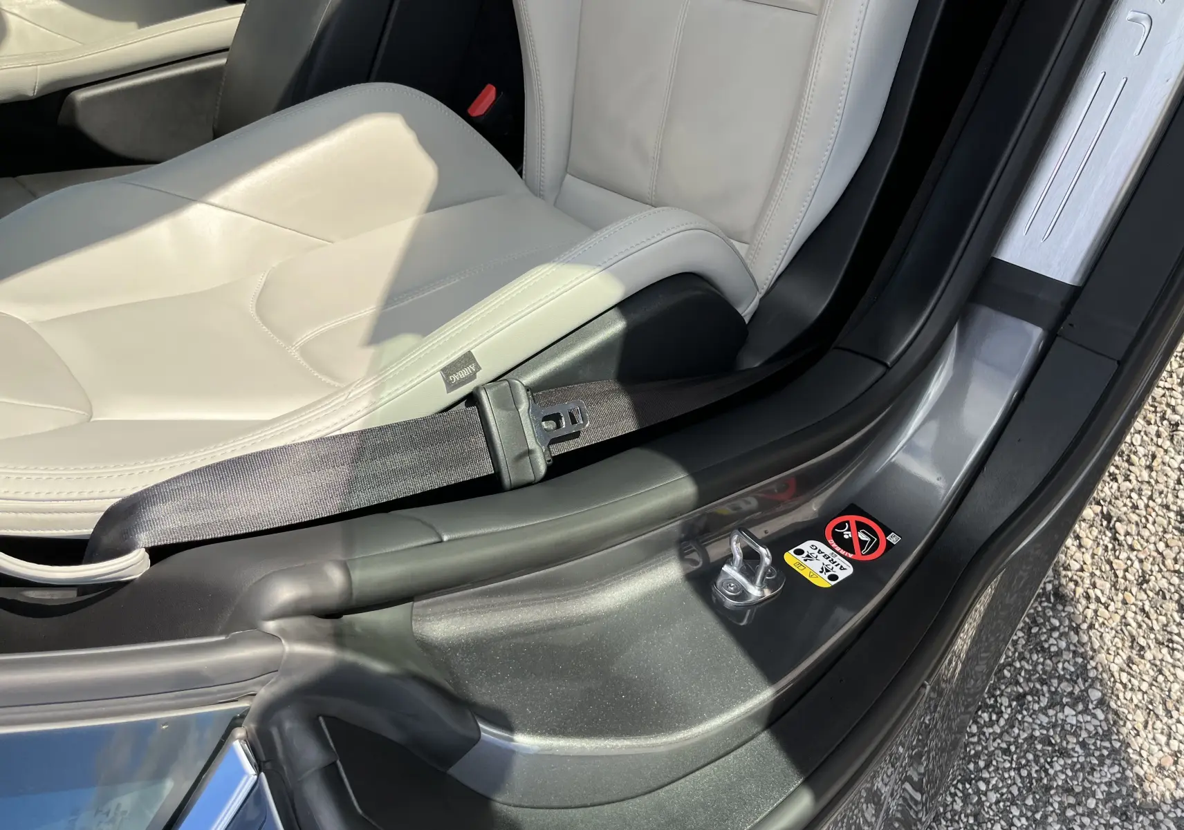Gros plan sur l'intérieur côté droit de la Jaguar F-TYPE gris Corris, montrant la sellerie cuir claire et la ceinture de sécurité.
