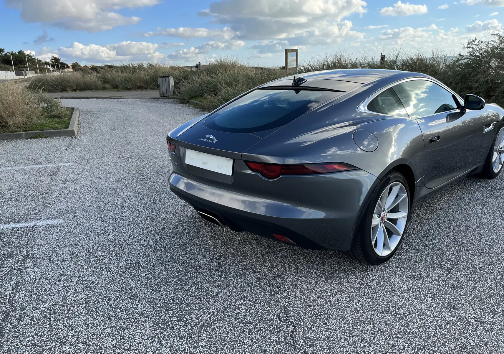 Jaguar F-TYPE II Coupé 2.0T 2018 gris Corris vue 3/4 arrière droit, jantes 19'' et échappement chromé visible.