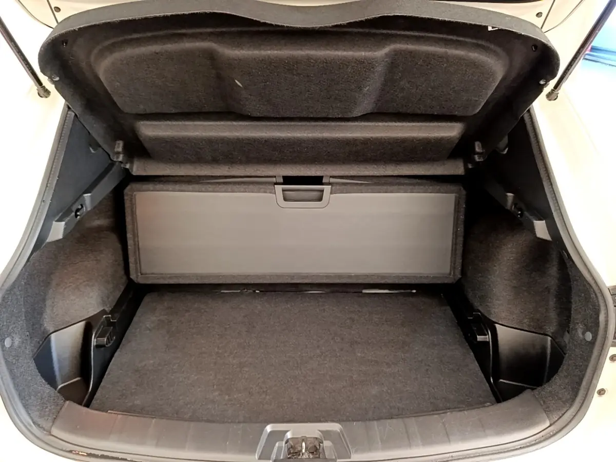 Coffre ouvert vu de face d'un Nissan Qashqai blanc, montrant l'espace de rangement et la tablette arrière.