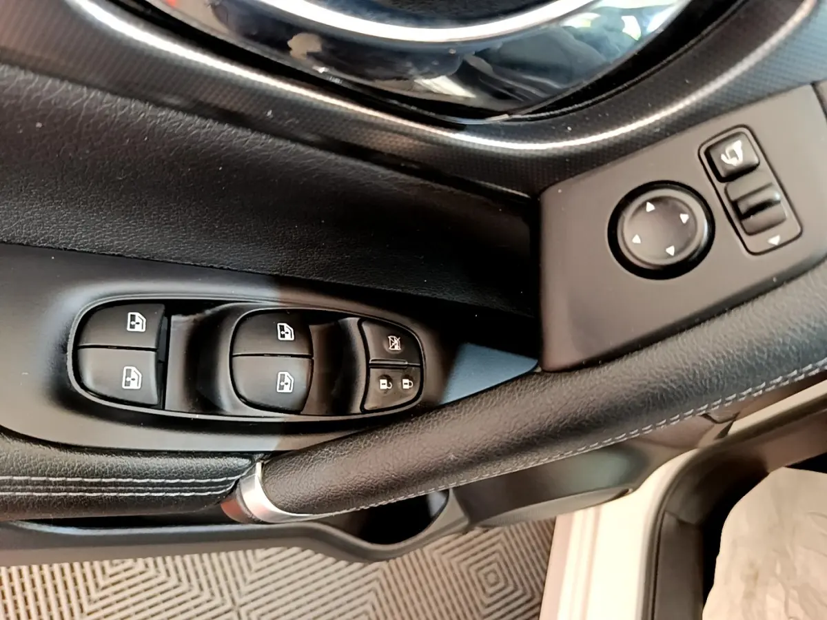 Gros plan sur la porte côté conducteur du Nissan Qashqai blanc, montrant les commandes des vitres et rétroviseurs.