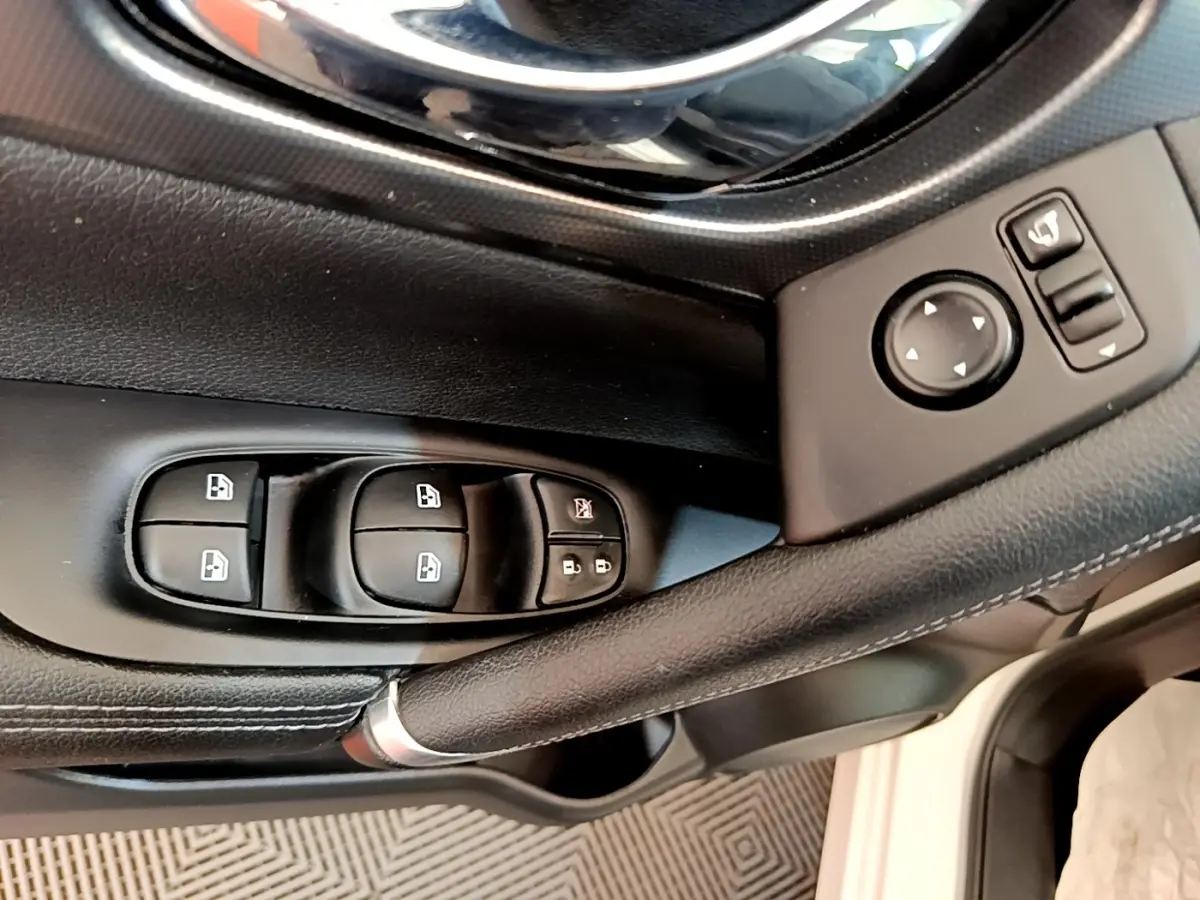 Gros plan sur la commande des vitres et rétroviseurs côté conducteur du Nissan Qashqai blanc, version 2019.