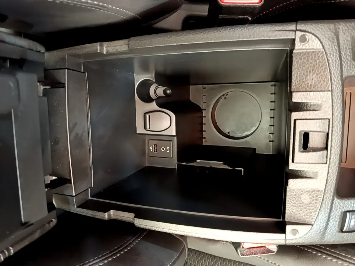 Vue plongeante sur le rangement central noir du Nissan Qashqai 1.3 DIG-T 140 Tekna avec prise USB et AUX intégrées.