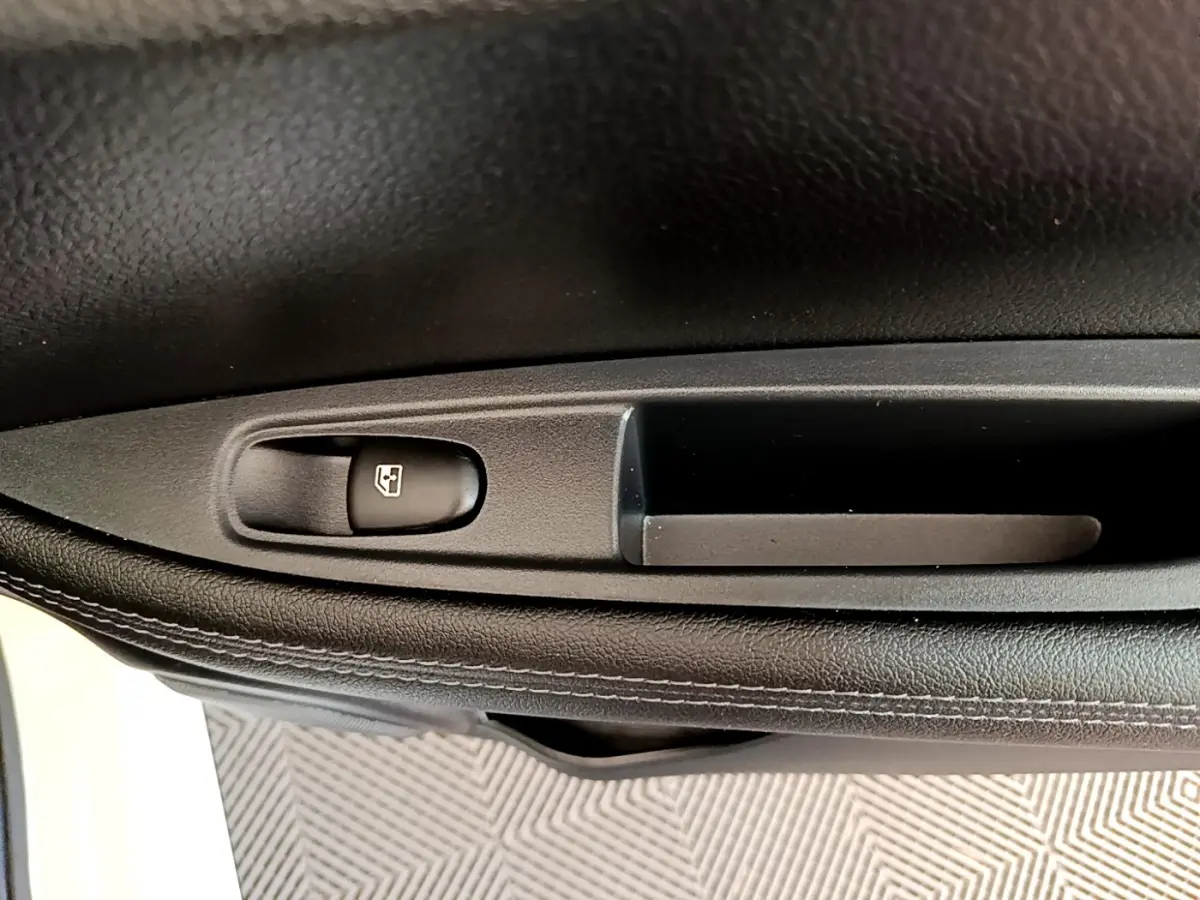 Détail de la commande de lève-vitre sur la porte intérieure côté conducteur d’un Nissan Qashqai blanc 2019.