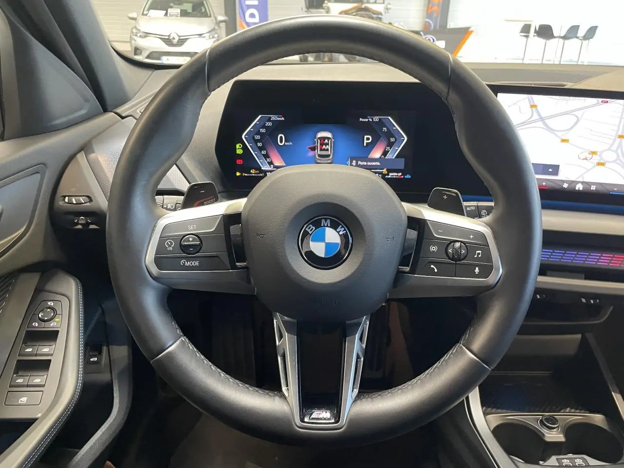 Vue intérieure centrée sur le volant cuir noir de la BMW Série 1 120d M Sport 2025 avec tableau de bord numérique.