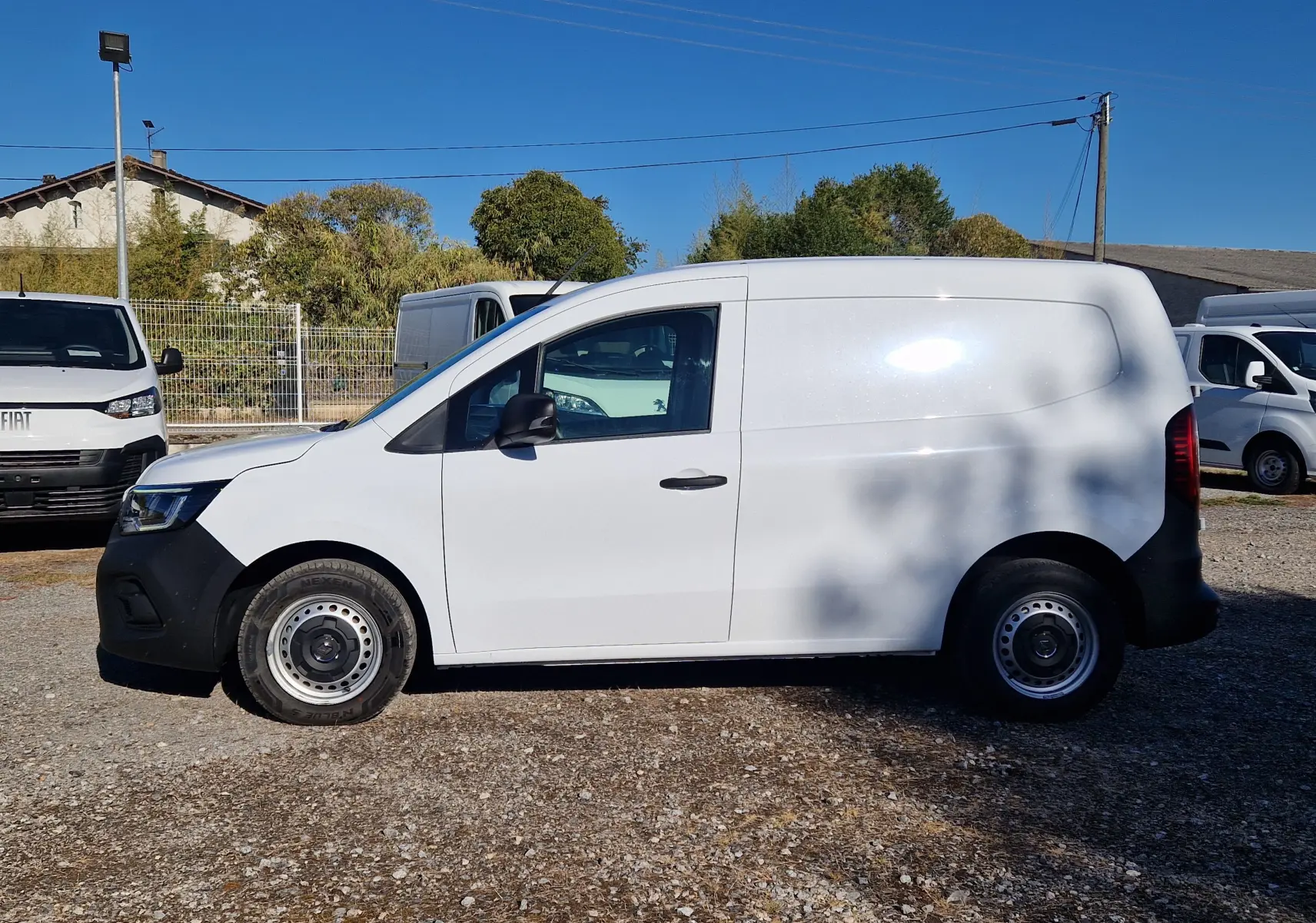 Profil latéral droit d'un Renault Kangoo blanc 2023 version Van, avec porte latérale coulissante et jantes acier simples.