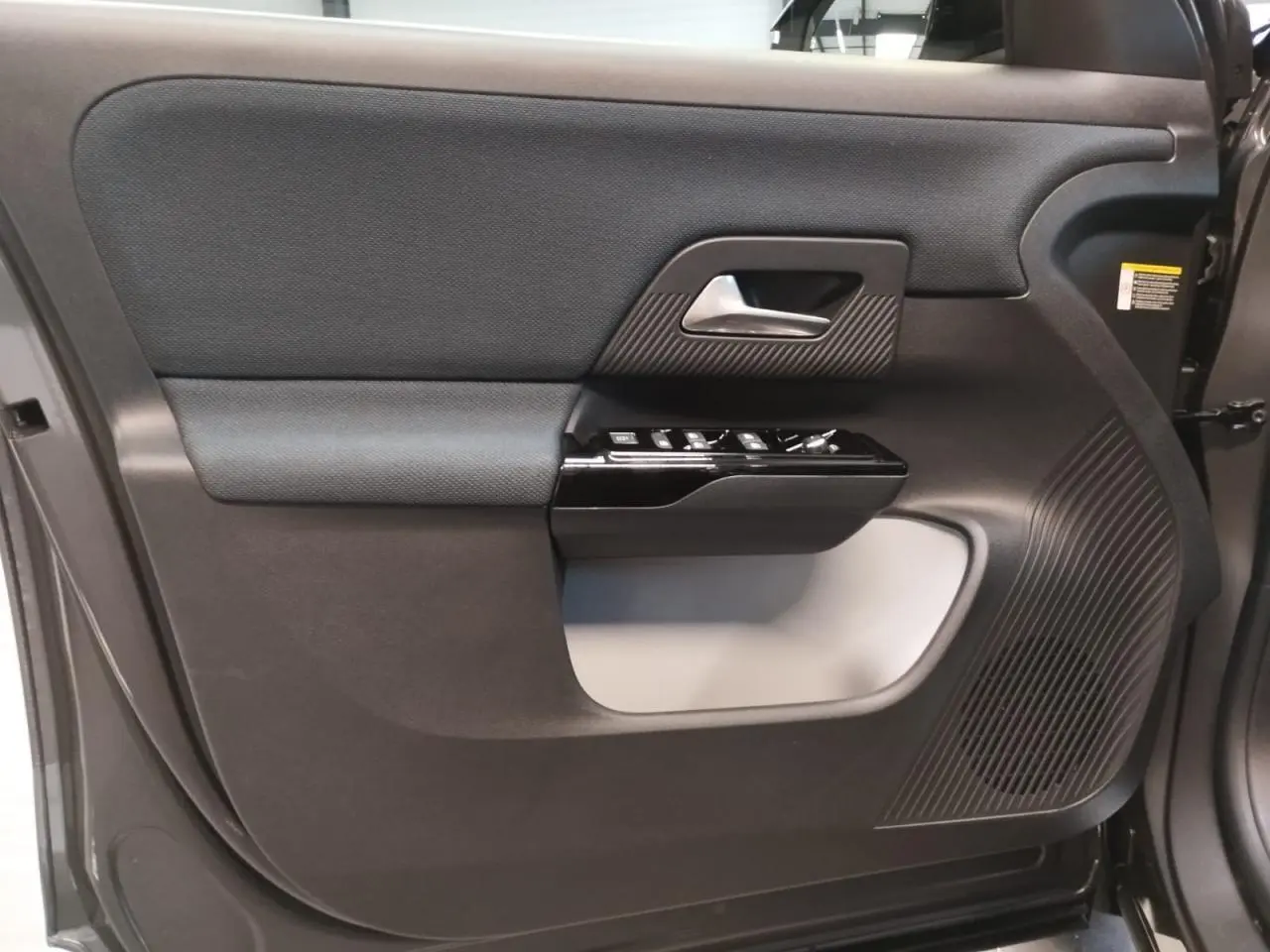 Gros plan sur la porte avant gauche du Citroën C5 Aircross gris platine, avec commandes de vitres et haut-parleur intégrés.