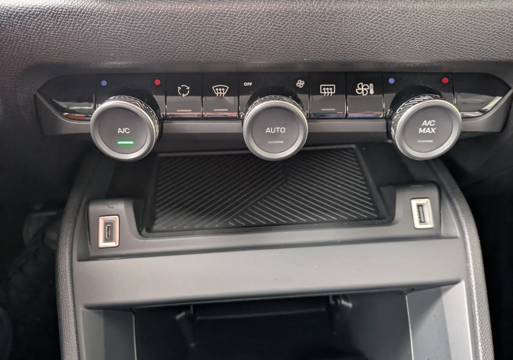 Vue plongeante sur la console centrale noire brillante de la Citroën C4 Hybrid 145, avec sellerie tissu gris et commandes de boîte auto.