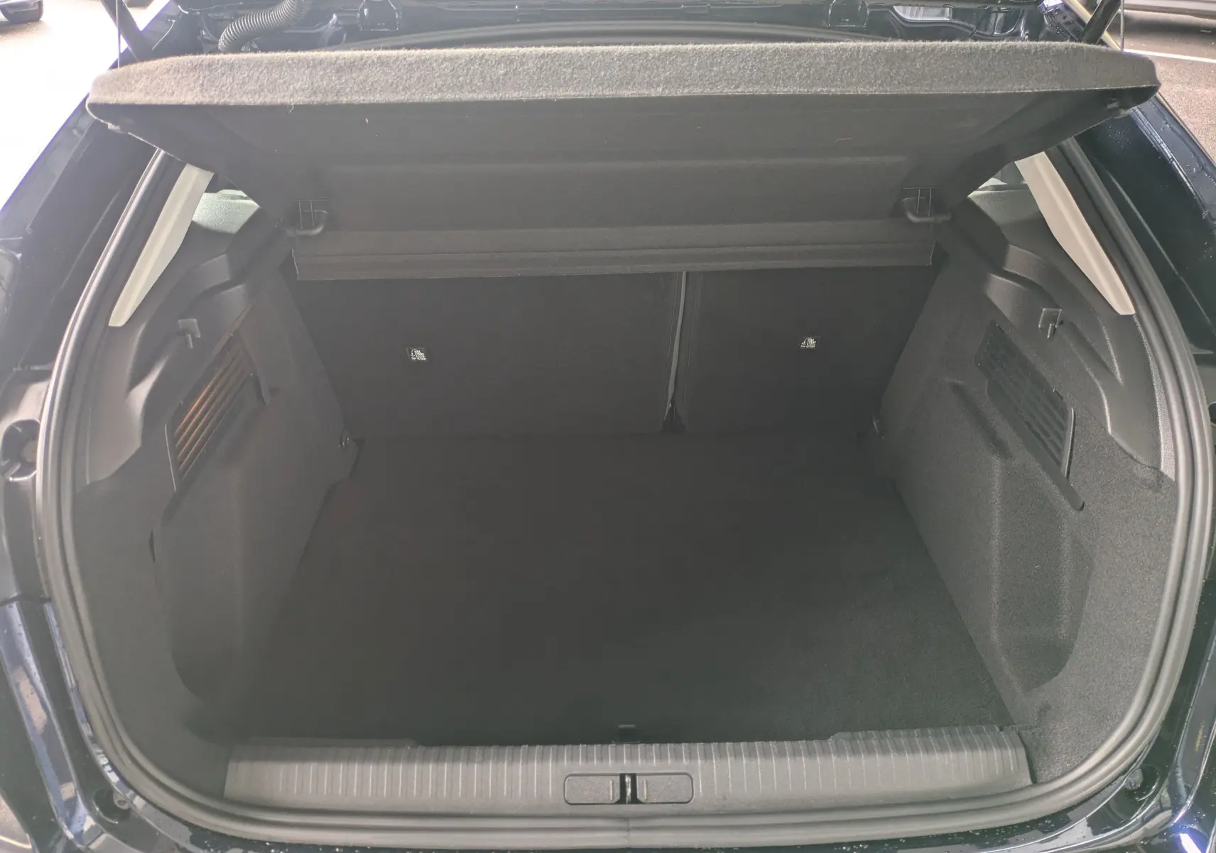 Coffre ouvert vu de l'arrière d'une Citroën C4 Hybrid 145 bleu foncé, montrant un espace de chargement vide.