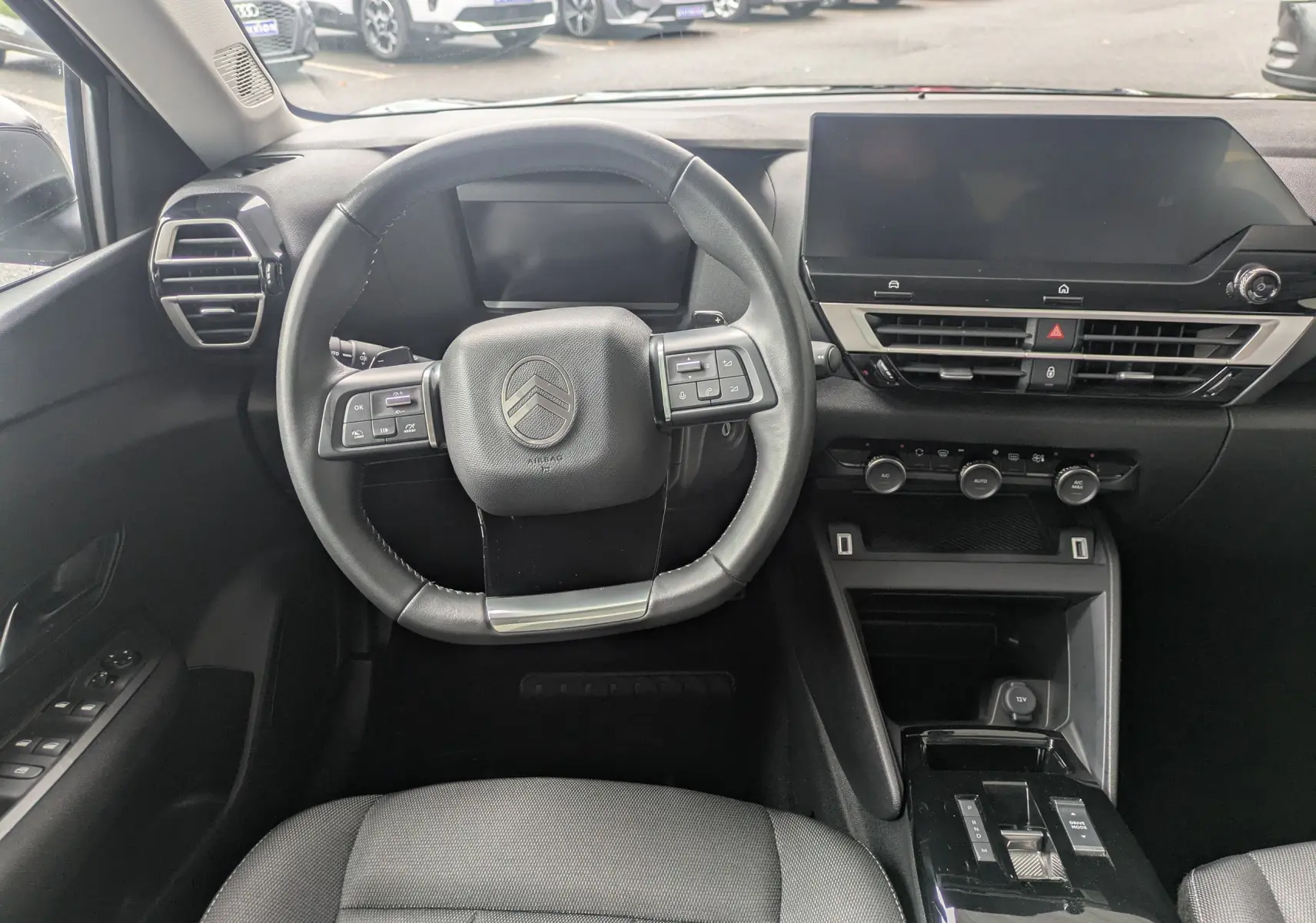 Vue intérieure avant centrée sur le volant et tableau de bord noir de la Citroën C4 Hybrid 145 E-DCS6 Plus 2025.