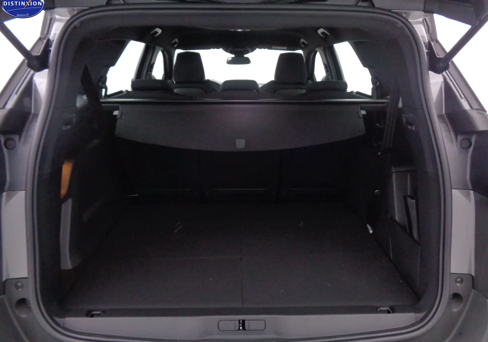 Coffre ouvert d'un Peugeot 5008 gris platinium, vue arrière montrant l'espace de chargement et la banquette arrière.