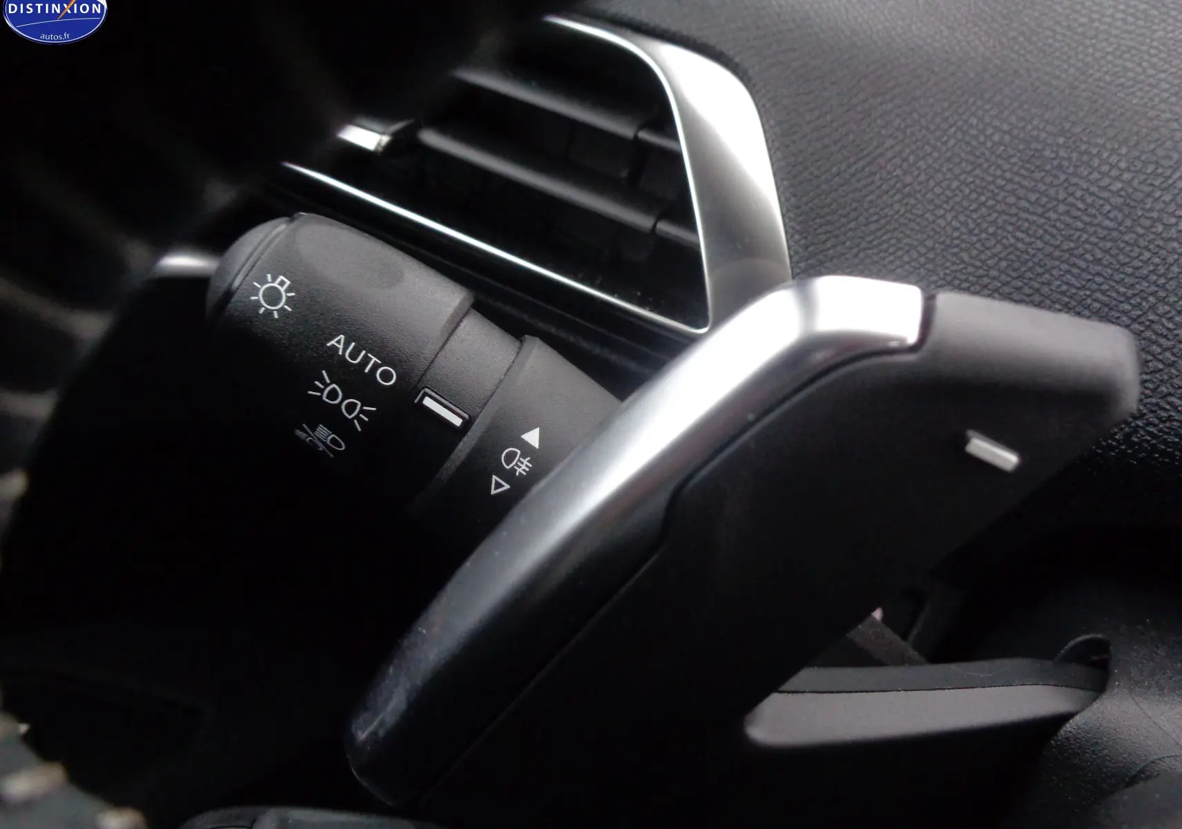 Gros plan sur la commande des feux et la palette de changement de vitesse dans l'habitacle du Peugeot 5008 gris platinium 2023.