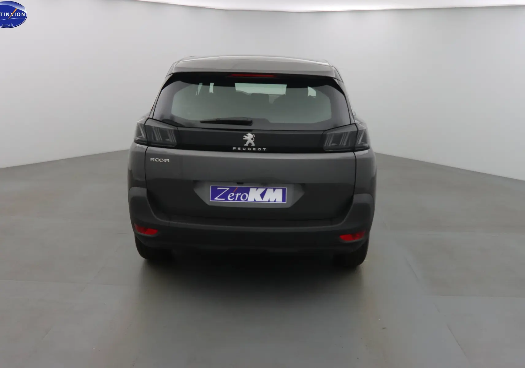Vue arrière d'un Peugeot 5008 gris platinium métal 2023 avec feux arrière sombres et plaque Zero KM.