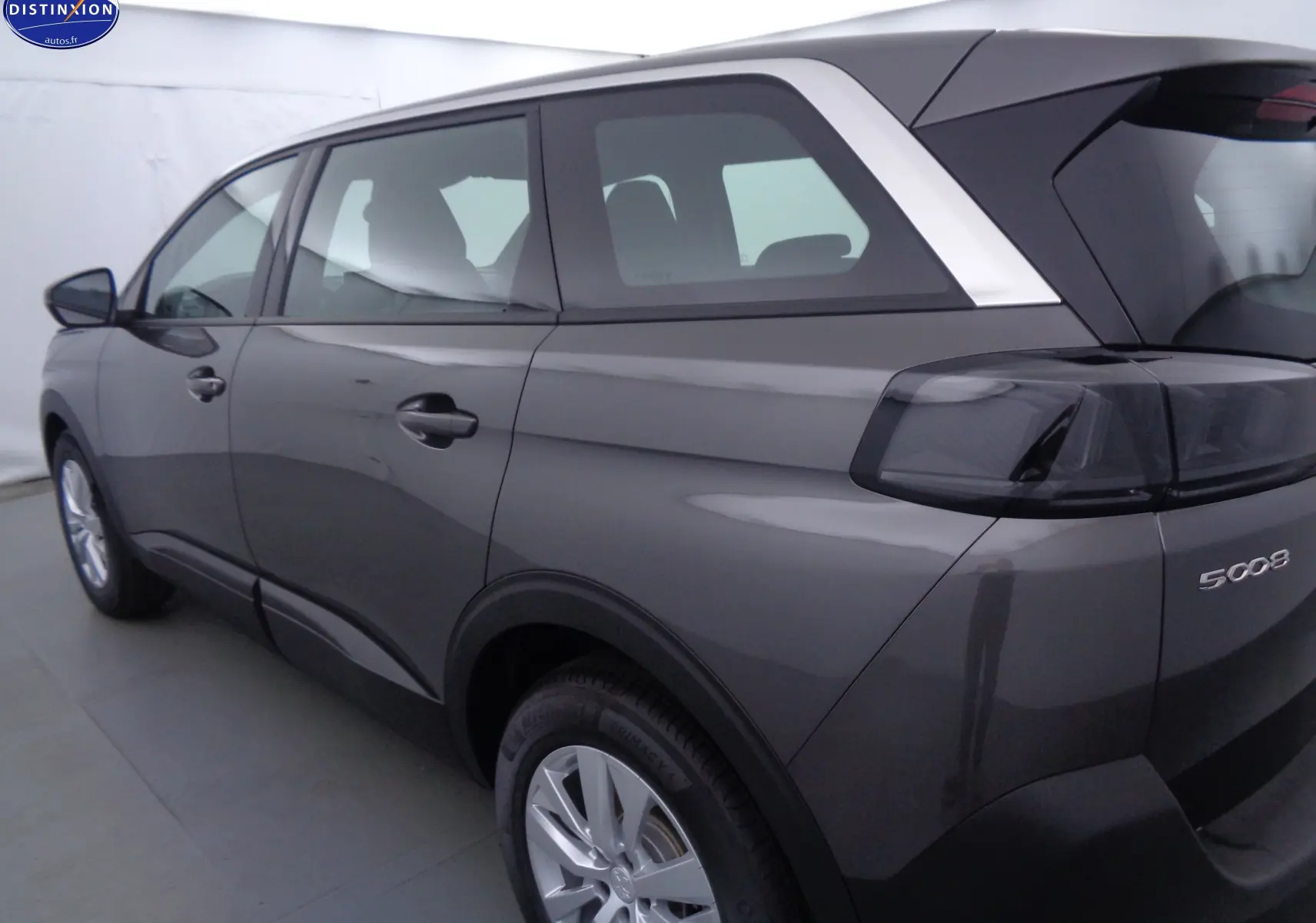 Vue latérale droite arrière du Peugeot 5008 gris platinium métal, mettant en valeur ses feux arrière fumés et ses lignes épurées.