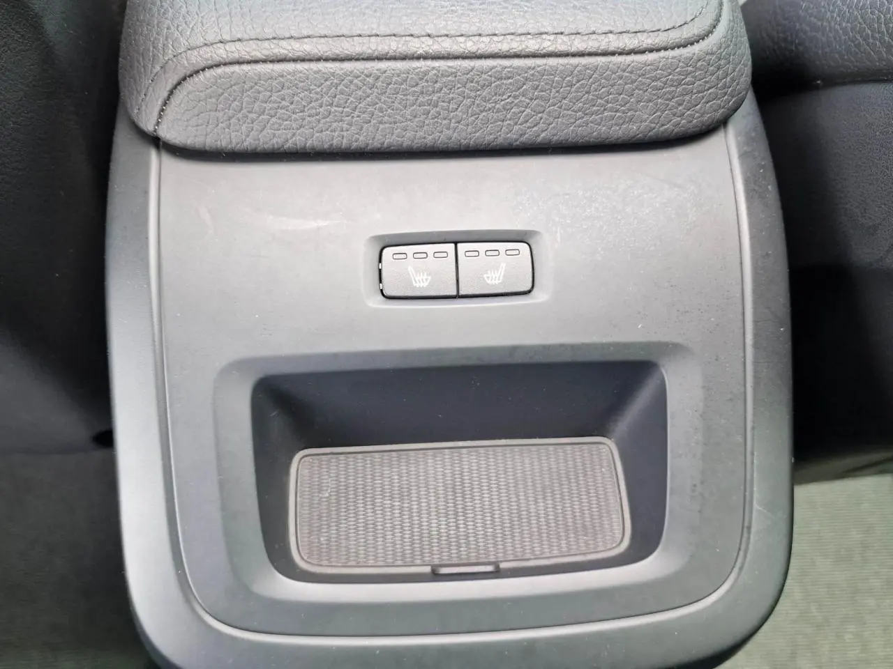 Gros plan sur la console centrale noire du Volvo XC60 II avec commandes des sièges chauffants arrière.