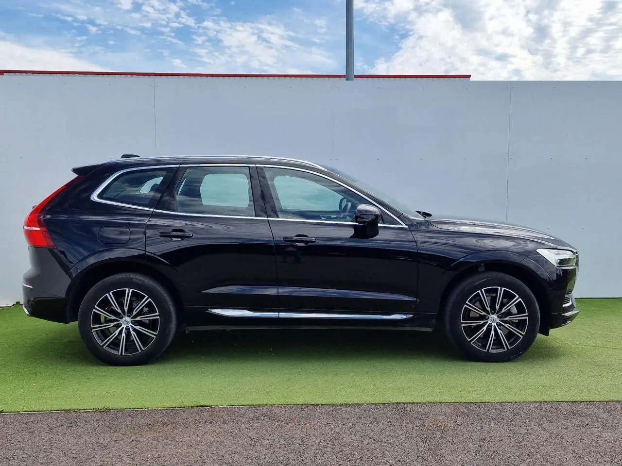 Profil côté gauche d'un Volvo XC60 noir 2021 avec jantes alliage 19 pouces et toit panoramique.