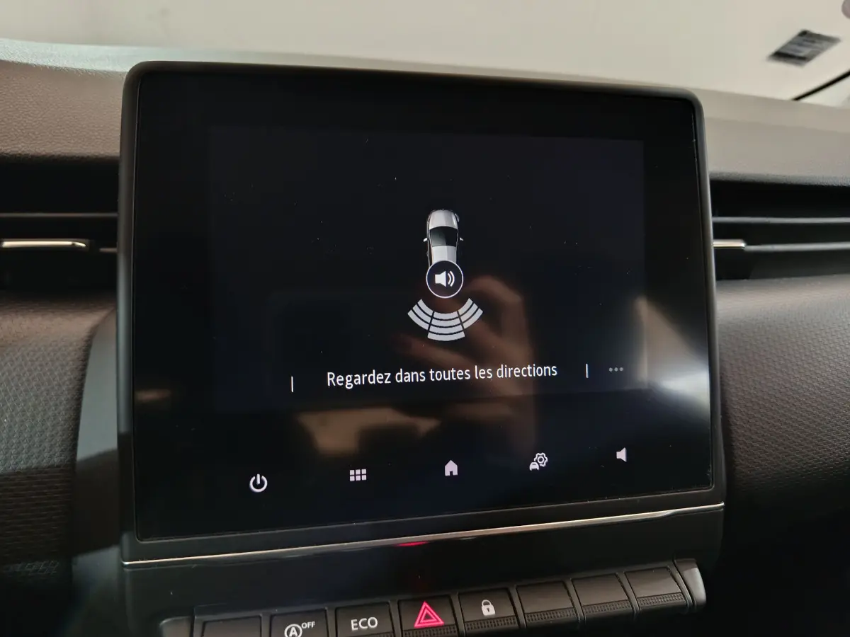 Écran tactile central de la Renault Clio Business blanc, affichant l'alerte de surveillance des alentours du véhicule.