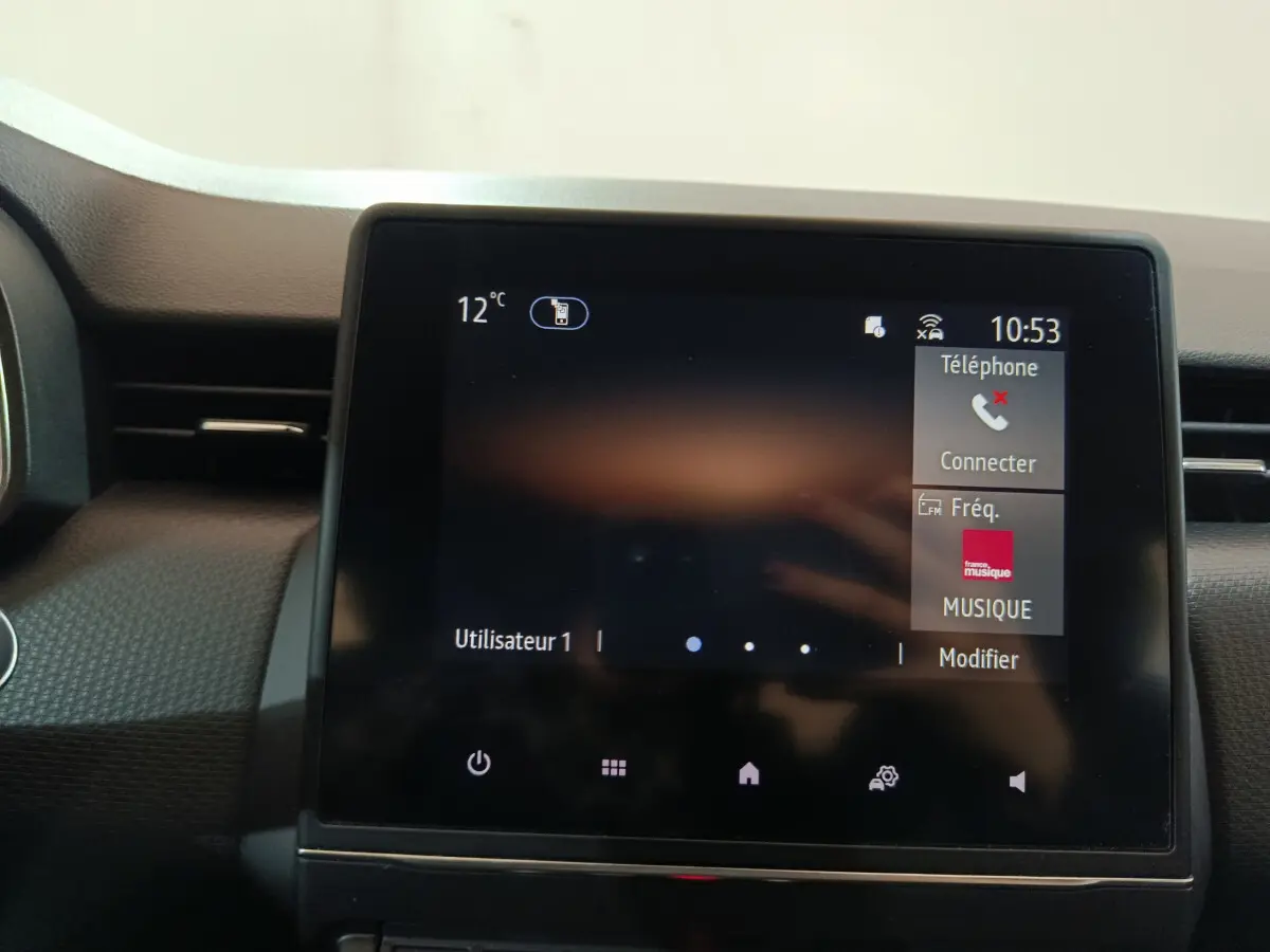 Écran tactile central du tableau de bord de la Renault Clio Business TCe 90 blanc, affichant téléphone et musique