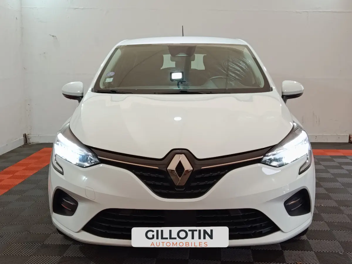 Vue frontale d'une Renault Clio Business TCe 90 blanche avec phares LED allumés dans un showroom.