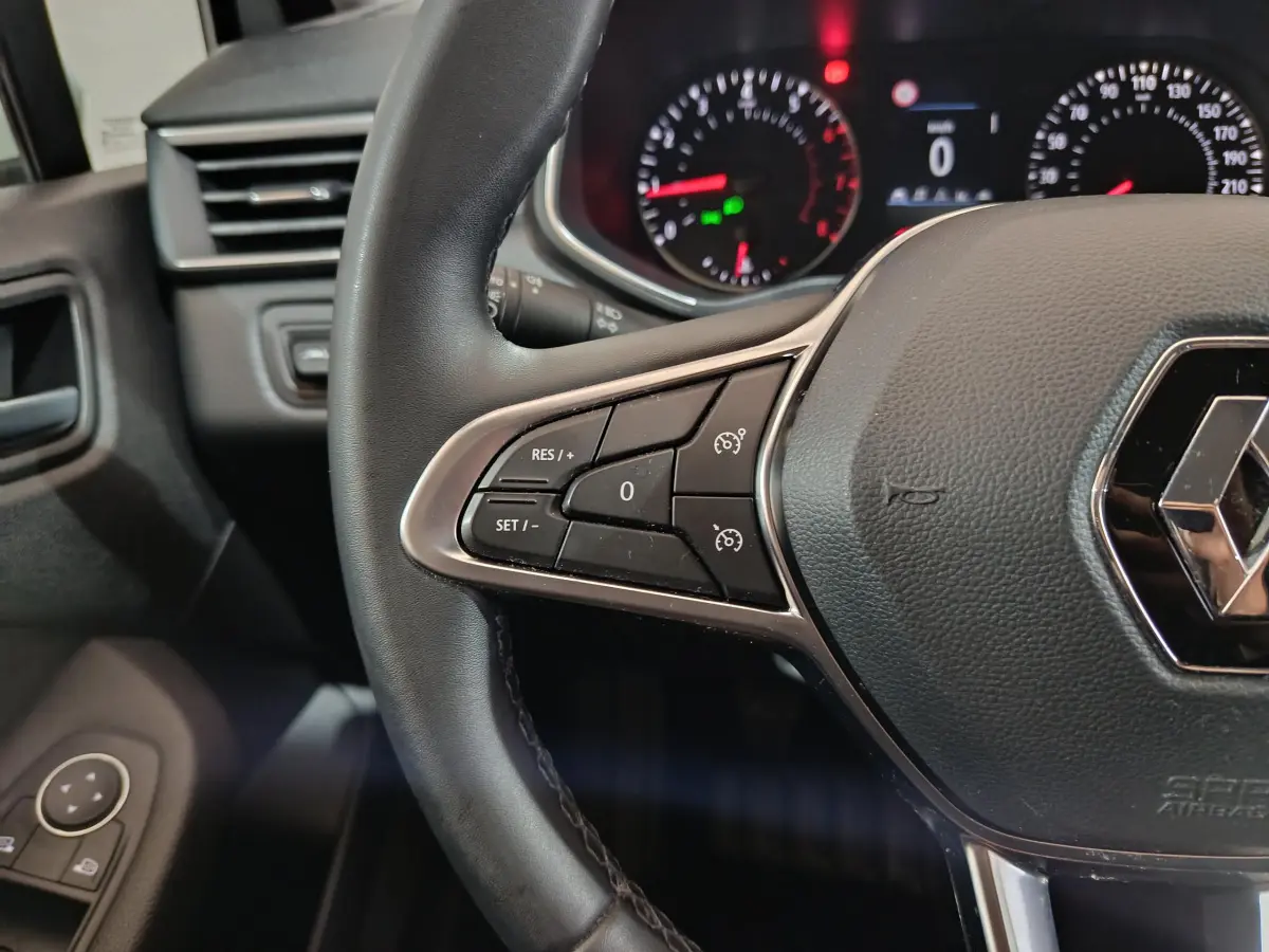 Gros plan sur le volant cuir noir de la Renault Clio Business TCe 90 2021, avec commandes de régulateur de vitesse.