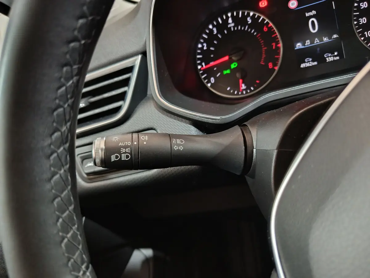 Gros plan sur la manette de phares et clignotants à gauche du volant cuir de la Renault Clio Business blanche 2021.