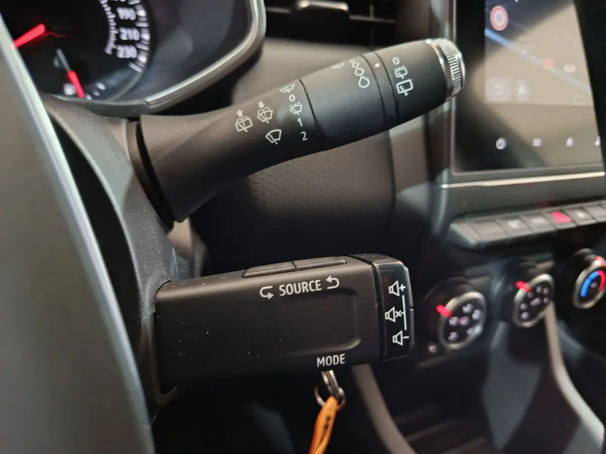 Gros plan sur les commandes au volant de la Renault Clio Business TCe 90 blanc, avec tableau de bord et écran tactile visibles.