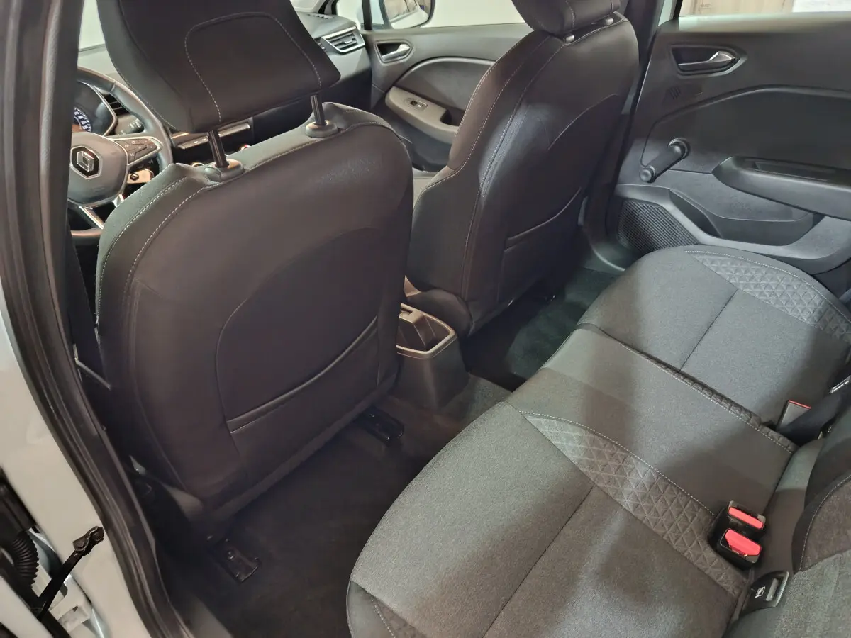 Vue intérieure arrière côté droit de la Renault Clio Business blanche, montrant la banquette arrière noire et les dossiers des sièges avant.