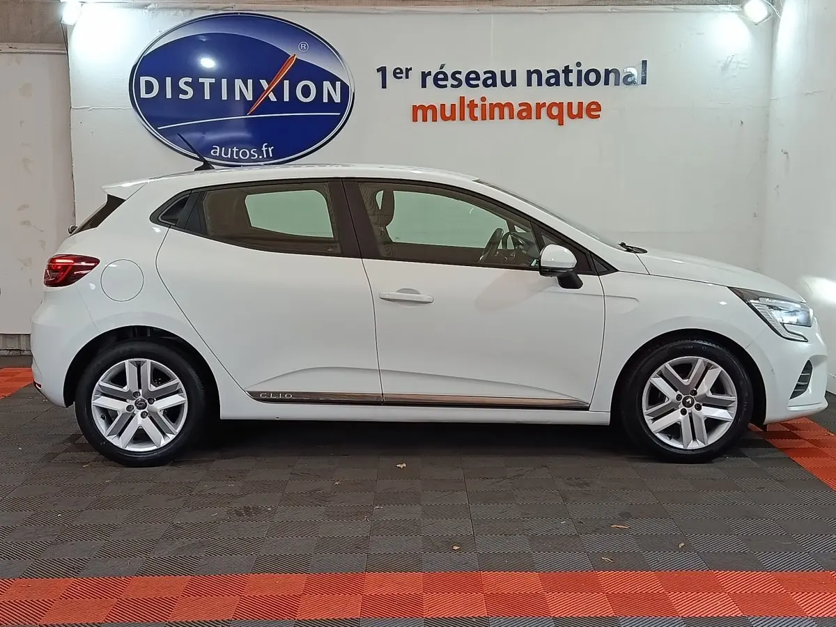 Profil droit d'une Renault Clio Business blanche 2021, avec jantes alliage et logo distinctif sous la porte arrière.