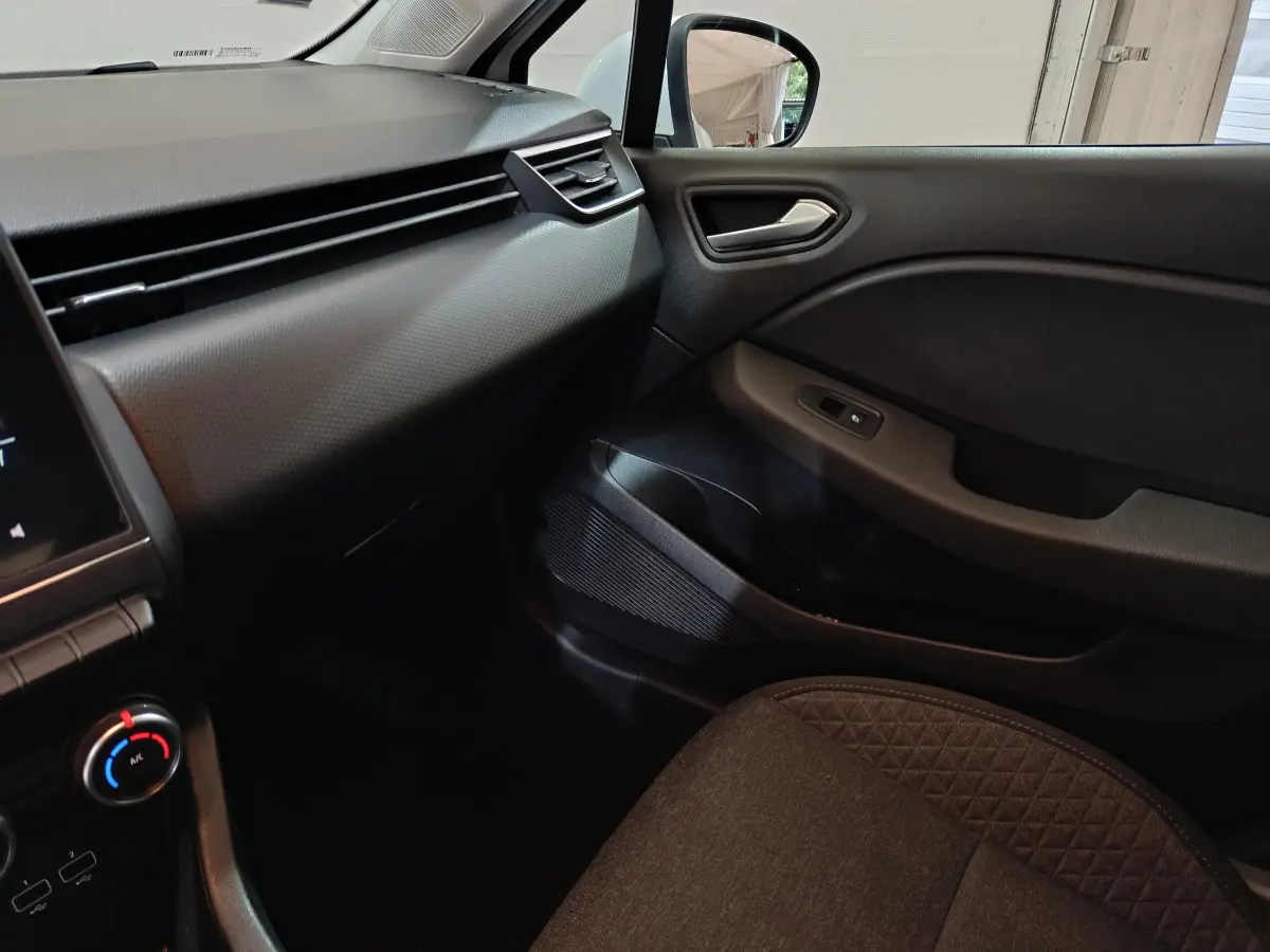 Intérieur côté passager de la Renault Clio Business TCe 90 blanc, tableau de bord et porte avec commandes visibles.