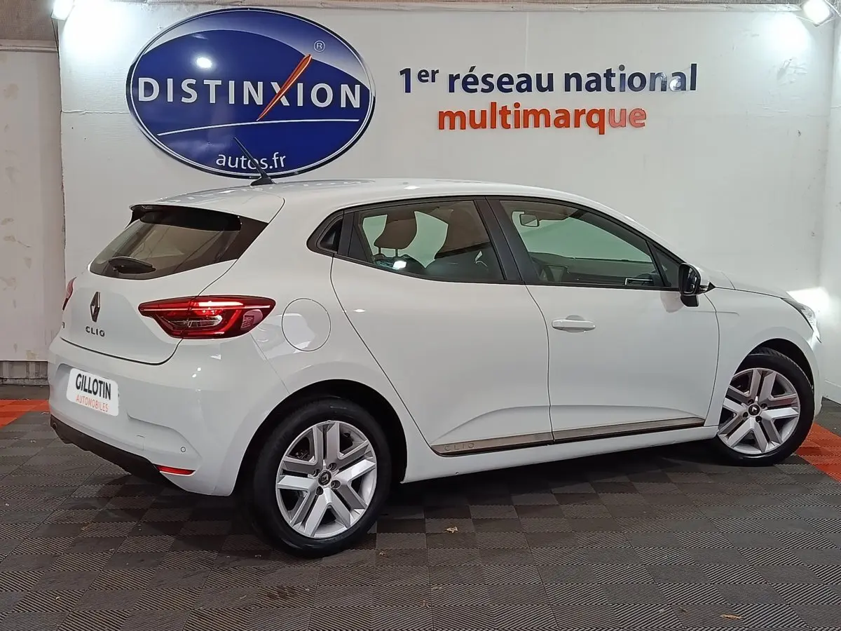 Renault Clio Business TCe 90 blanc vue de profil côté gauche en intérieur avec jantes alliage et feux arrière LED.