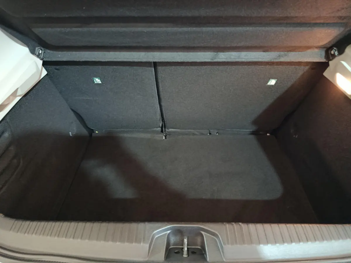 Coffre ouvert vu de face d'une Renault Clio Business TCe 90 blanche, intérieur noir et éclairage latéral.