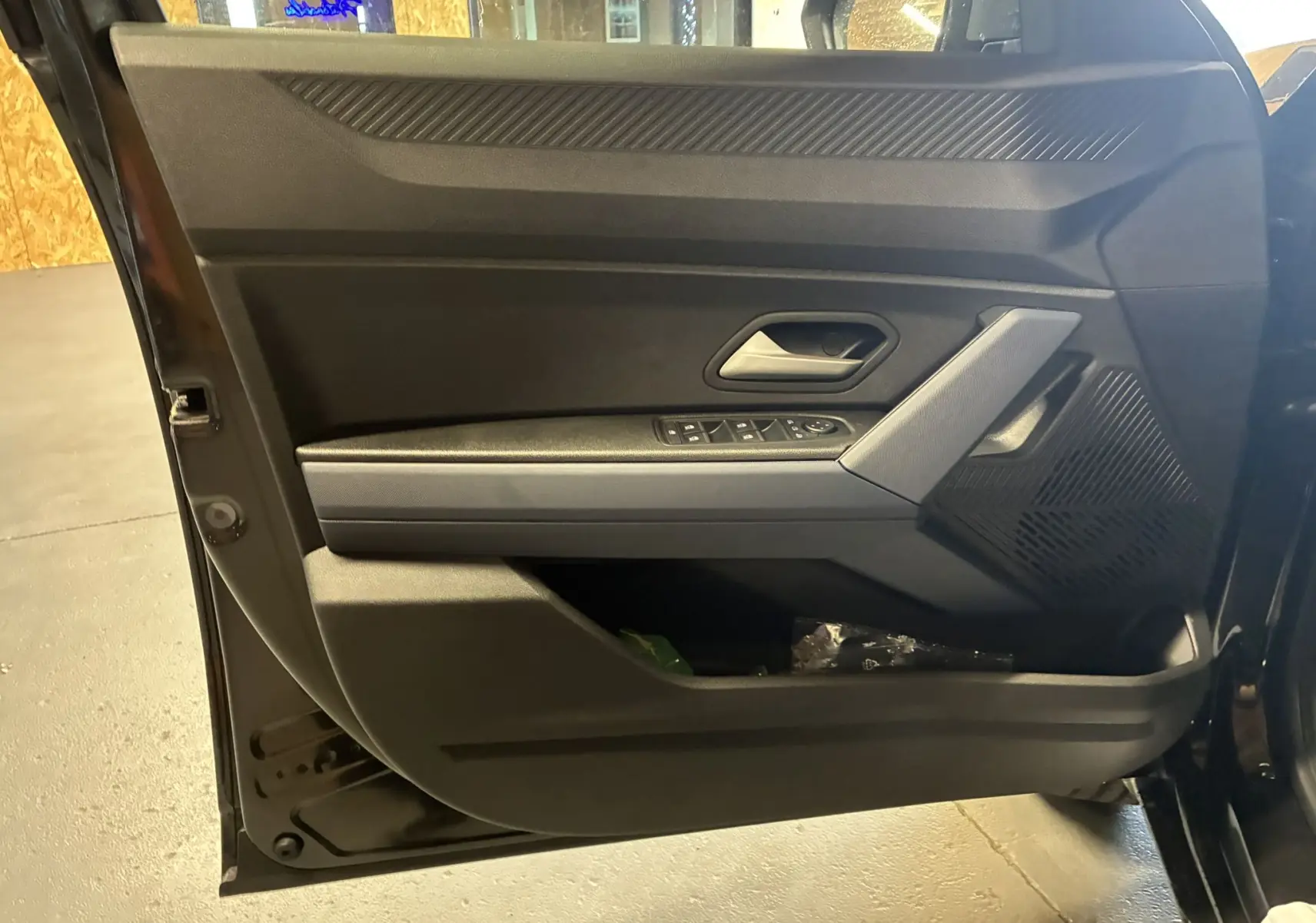 Dacia Duster 1.6 Hybrid noir en 3/4 avant droit, avec jantes noires et grises, dans un intérieur bois clair.