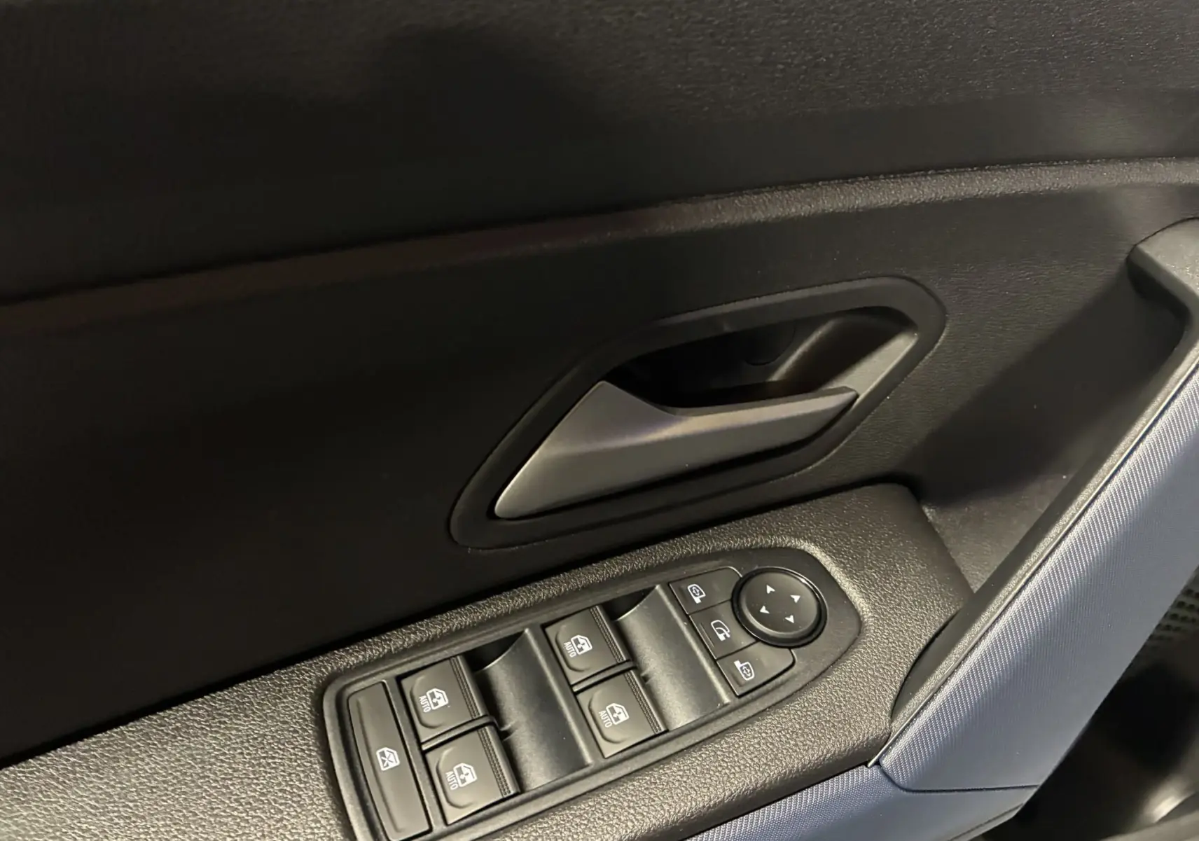 Vue avant d'un Dacia Duster 1.6 Hybrid 140 noir, avec calandre distinctive et phares allumés en intérieur showroom.