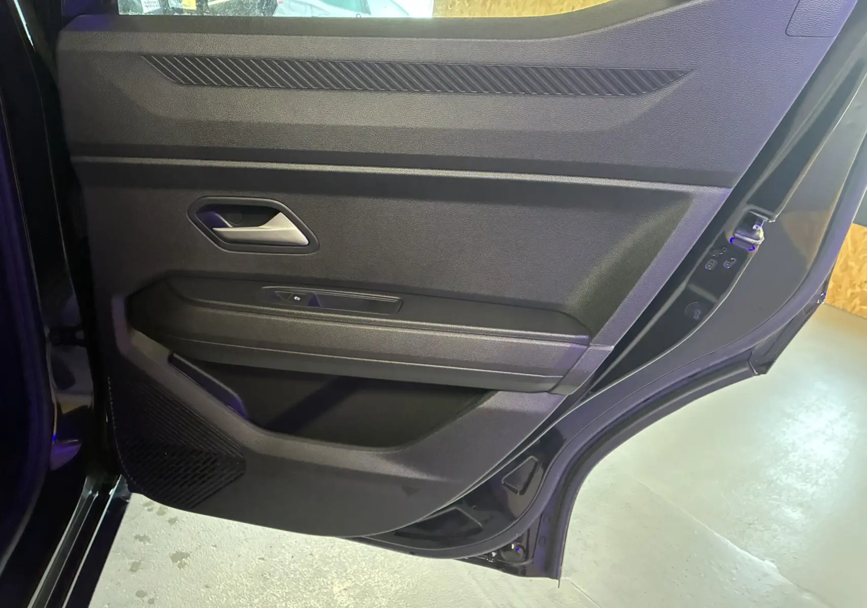 Vue intérieure de la porte arrière droite noire du Dacia Duster 1.6 Hybrid 140 Journey avec poignée et commande de vitre.