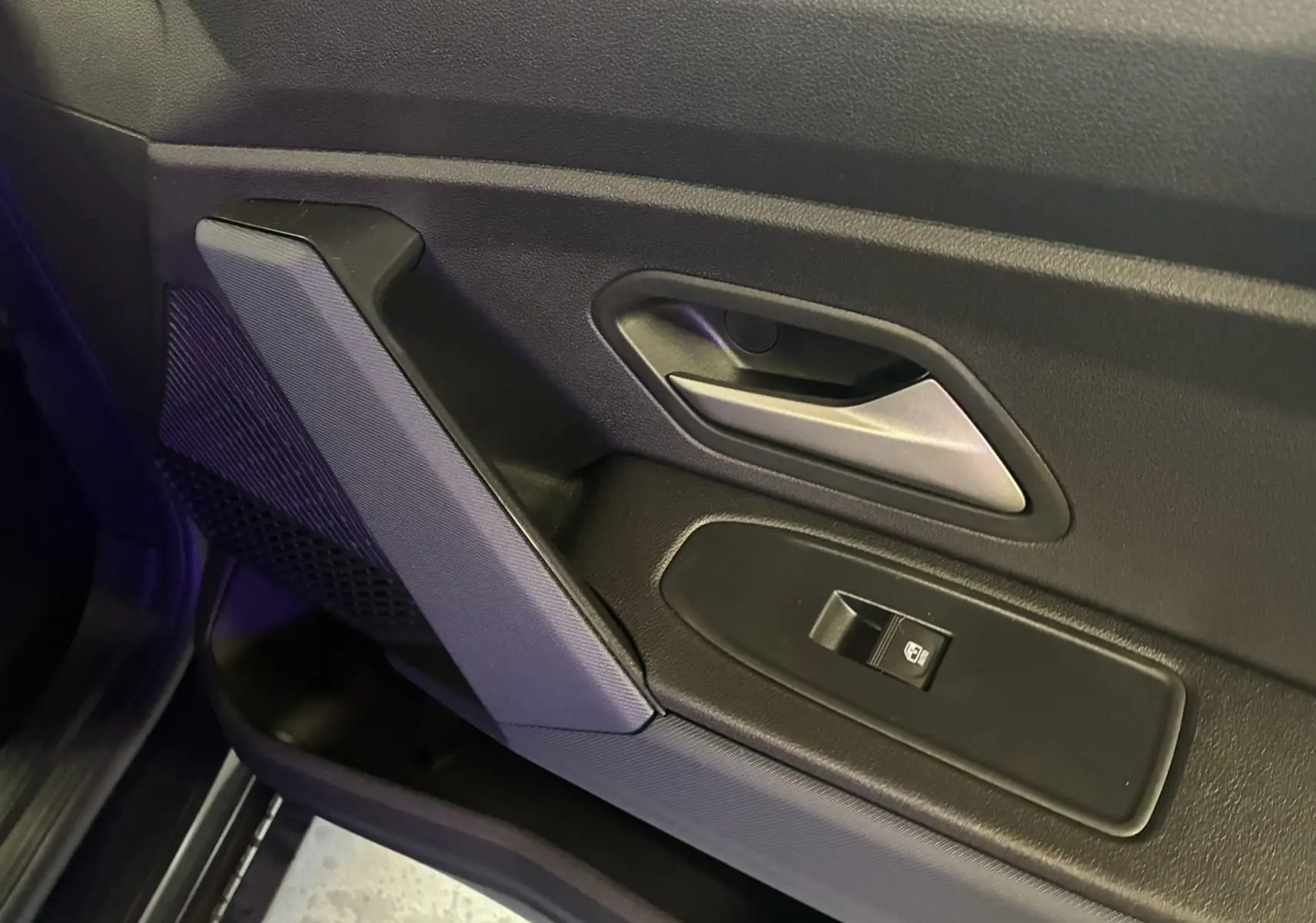 Gros plan sur la poignée intérieure et le bouton de lève-vitre côté gauche d’une porte noire du Dacia Duster 2025.