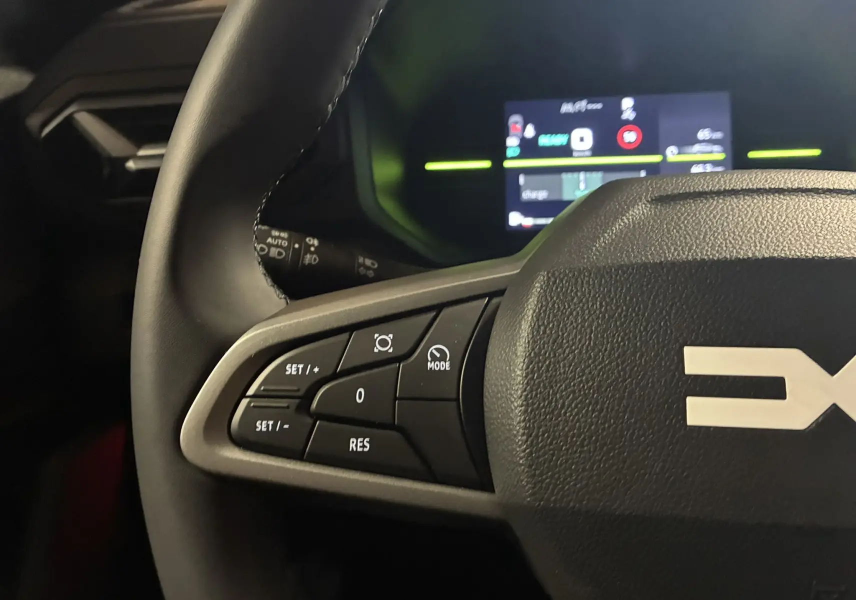 Gros plan sur le volant noir du Dacia Duster 1.6 Hybrid 140 Journey 2025, avec commandes de régulateur et tableau de bord numérique en arrière-plan.