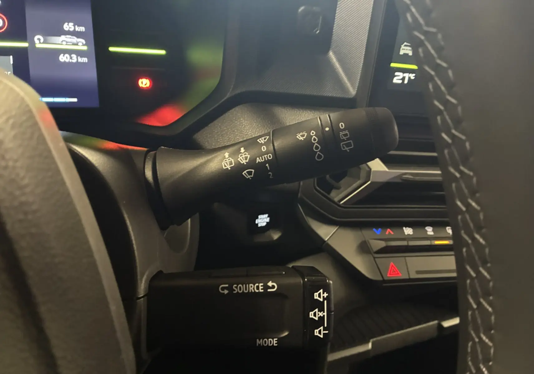 Gros plan sur les commandes au volant du Dacia Duster 1.6 Hybrid 140 Journey noir, avec tableau de bord digital et climatisation visible.