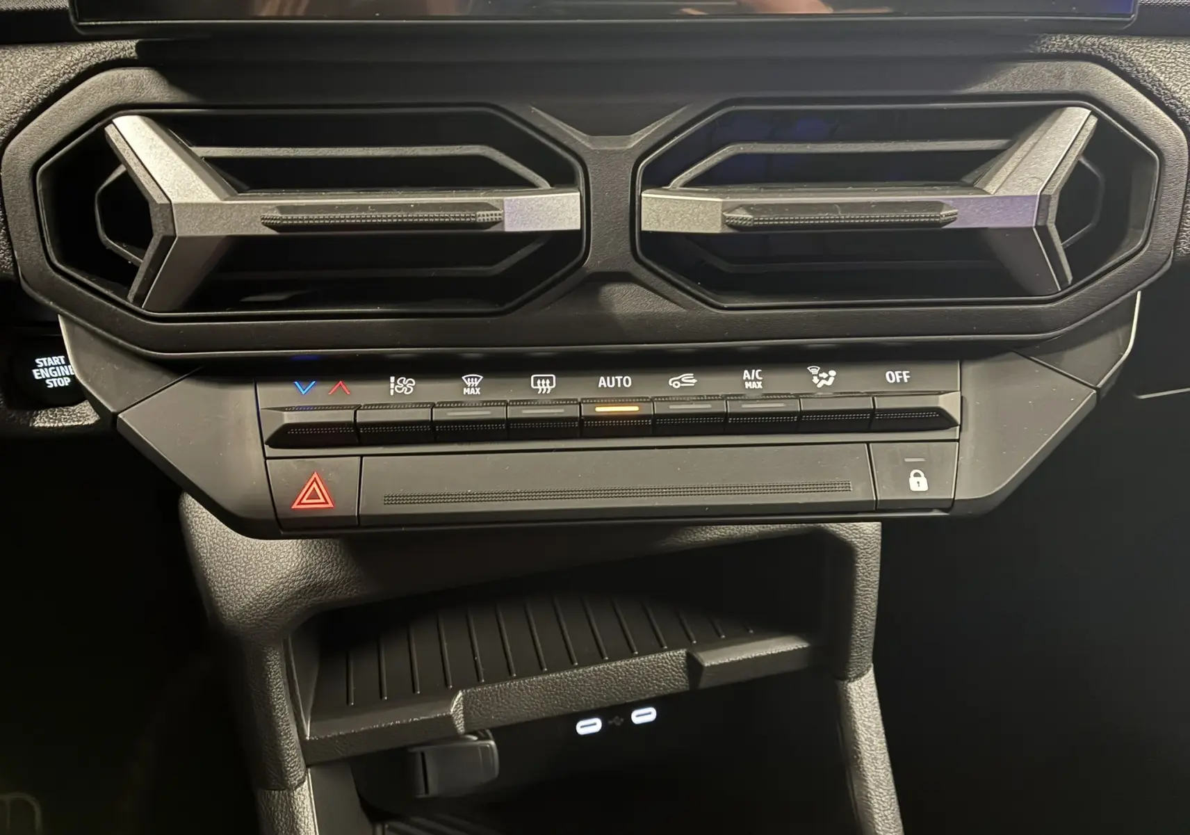 Gros plan sur la console centrale noire du Dacia Duster 2025, avec les aérateurs hexagonaux et les commandes de climatisation.