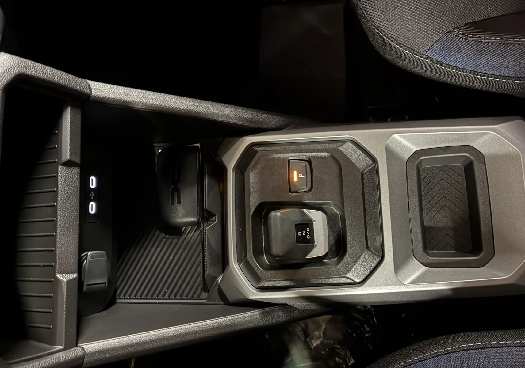 Vue rapprochée du levier de vitesses automatique et du frein de stationnement électrique sur la console centrale du Dacia Duster noir.