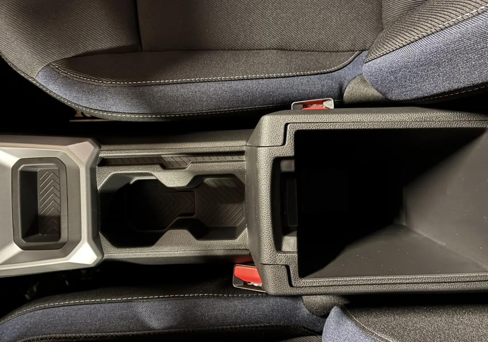 Vue plongeante sur la console centrale noire avec porte-gobelets et accoudoir ouvert du Dacia Duster 1.6 Hybrid 140 Journey.