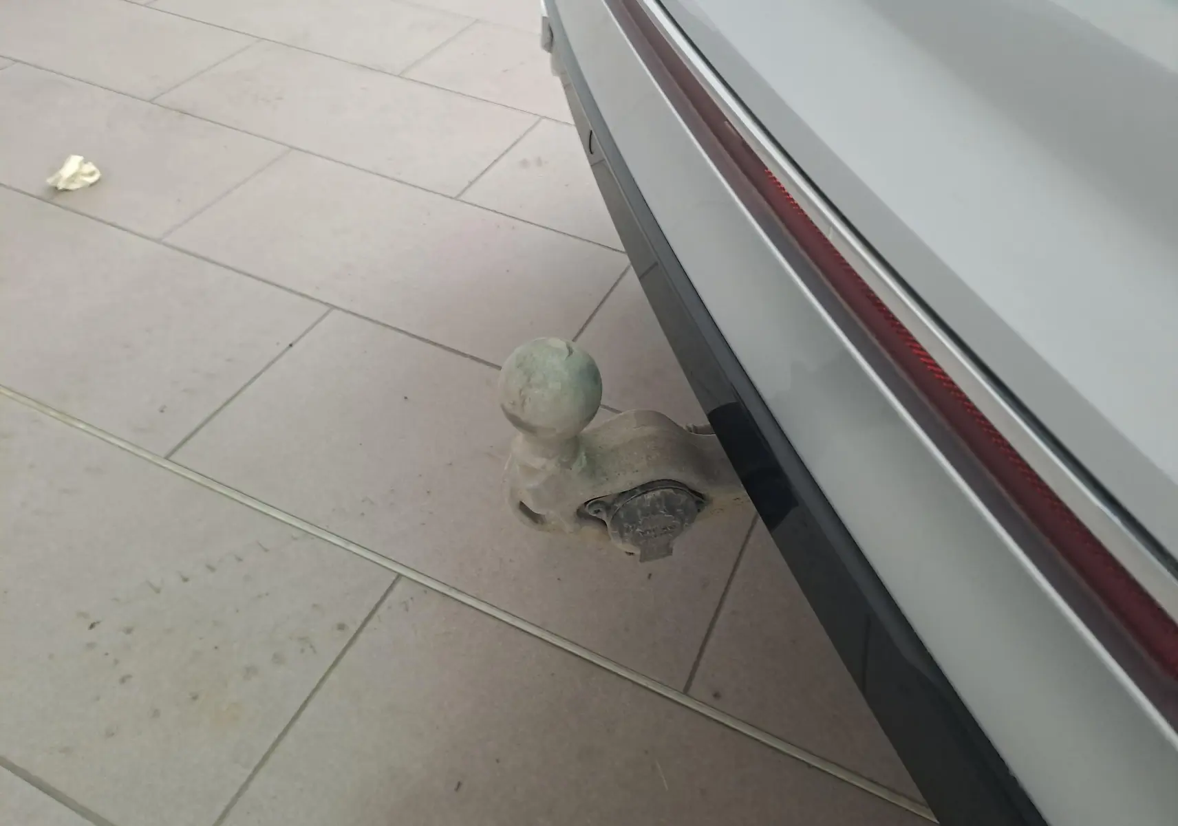 Gros plan sur le crochet d'attelage escamotable arrière du Volkswagen Tiguan 2024 en Reflet d'Argent, avec bande rouge de feu arrière.