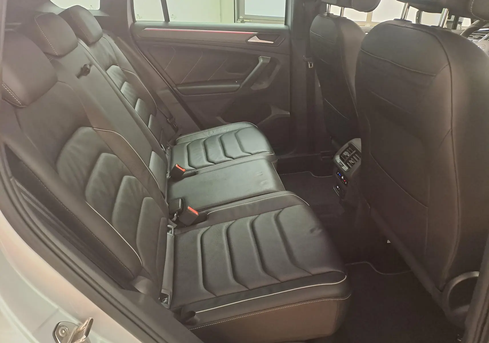 Vue intérieure côté gauche des sièges arrière en cuir noir du Volkswagen Tiguan 2024, soulignant l'espace et les finitions.