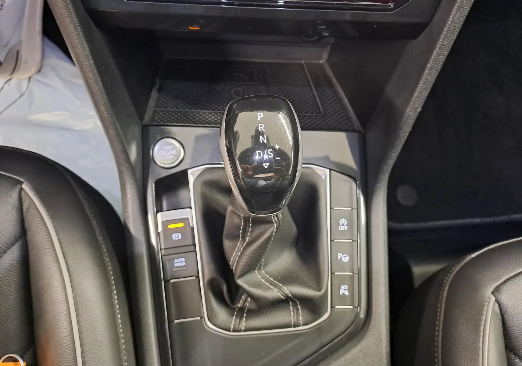 Gros plan sur le levier de vitesses automatique du Volkswagen Tiguan 2024, entouré de boutons de contrôle et cuir noir.
