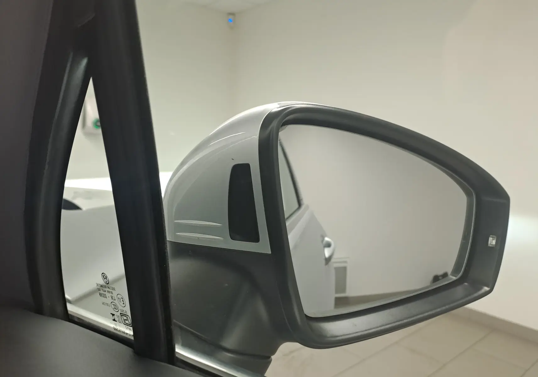 Rétroviseur côté gauche du Volkswagen Tiguan 2024 en Reflet d'Argent, avec carrosserie et poignée visibles en arrière-plan.