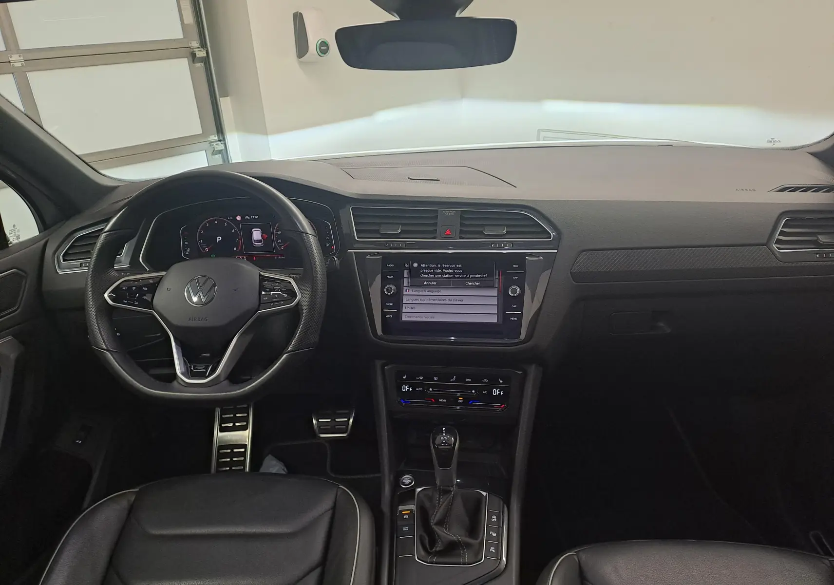 Vue intérieure frontale du Volkswagen Tiguan 2024, tableau de bord noir avec écran tactile et volant multifonction.