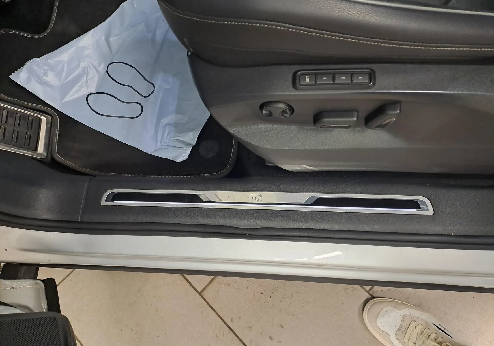 Vue rapprochée du seuil de porte côté conducteur du Volkswagen Tiguan 2024 en Reflet d'Argent avec réglages électriques du siège.
