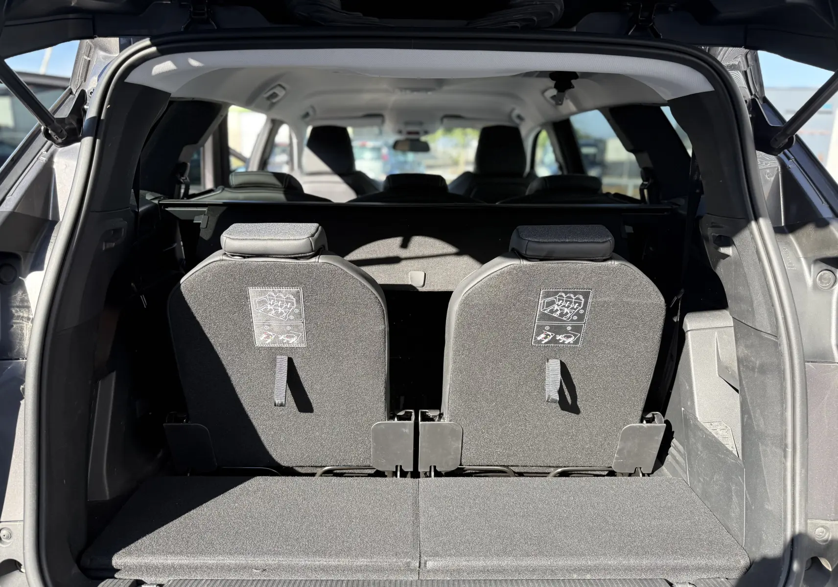 Vue arrière du coffre ouvert d’un Peugeot 5008 gris 2021, montrant les deux sièges arrière relevés et l’habitacle lumineux.