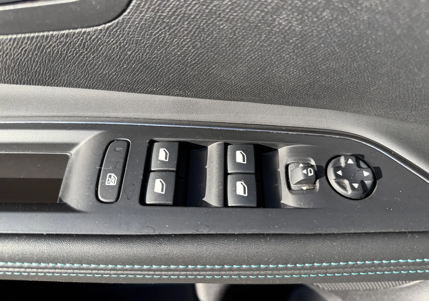 Gros plan sur les commandes de lève-vitres et réglage des rétroviseurs côté conducteur du Peugeot 5008 gris, intérieur noir.
