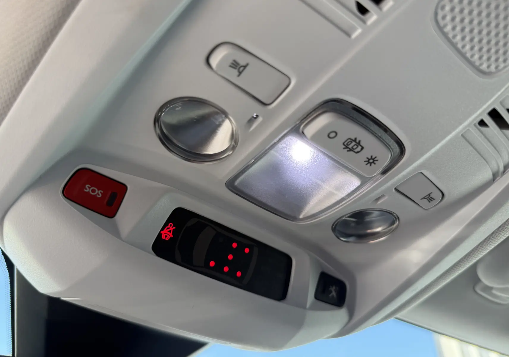 Vue en gros plan du plafonnier intérieur gris clair du Peugeot 5008 avec boutons SOS et éclairage LED allumé.
