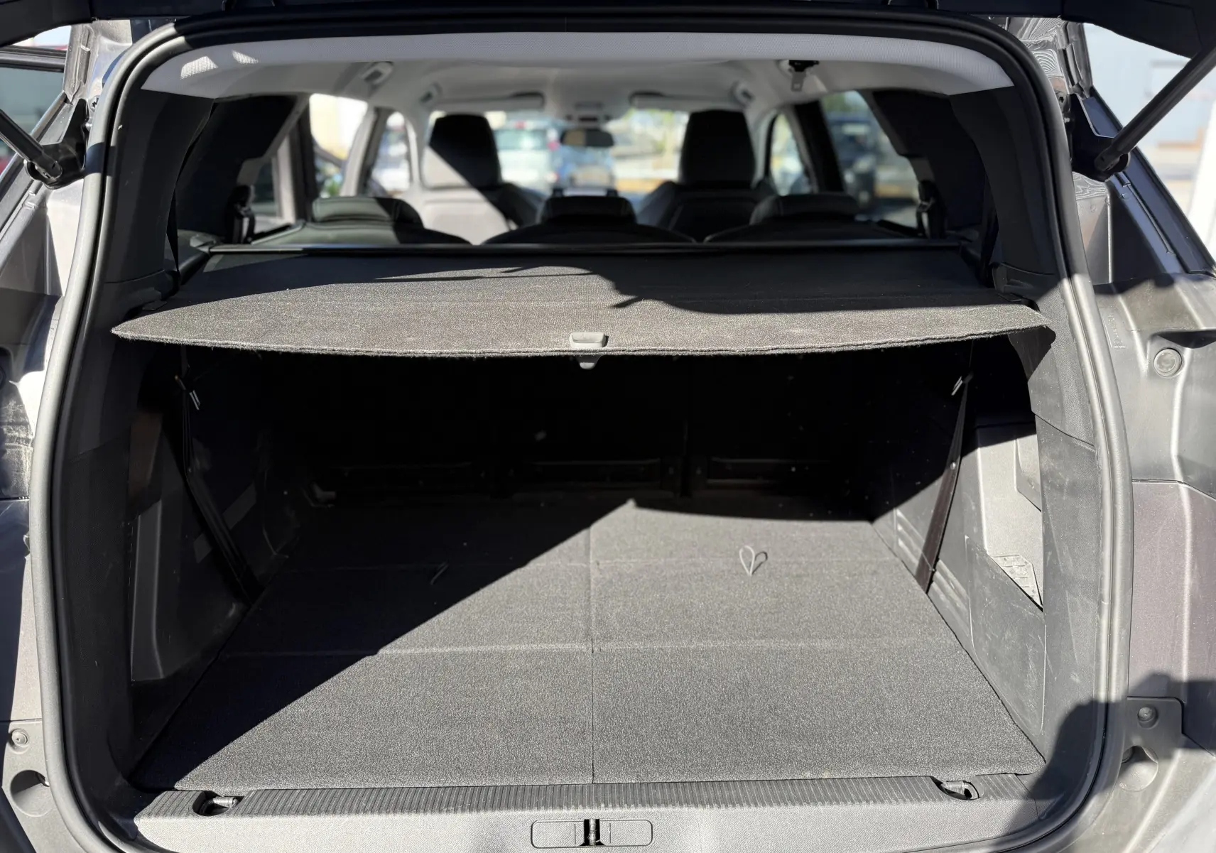 Coffre ouvert vu de l'arrière d'un Peugeot 5008 gris 2021, avec cache-bagages déployé et sièges arrière visibles.