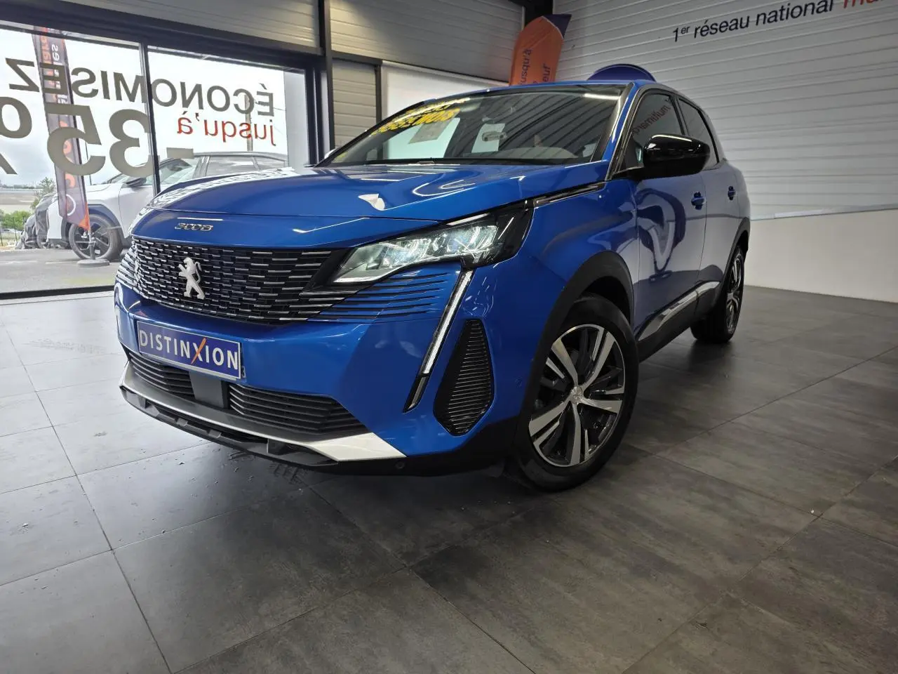 Peugeot 3008 Bleu Iron vue 3/4 avant droit, calandre chromée et jantes alliage bi-ton visibles en showroom.